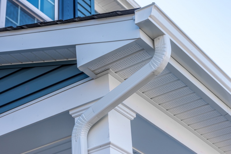 A closeup of white vinyl gutters and soffit on a blue house.