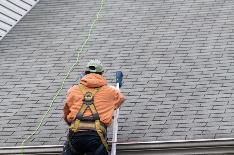 Man on Ladder Inspecting a Roof